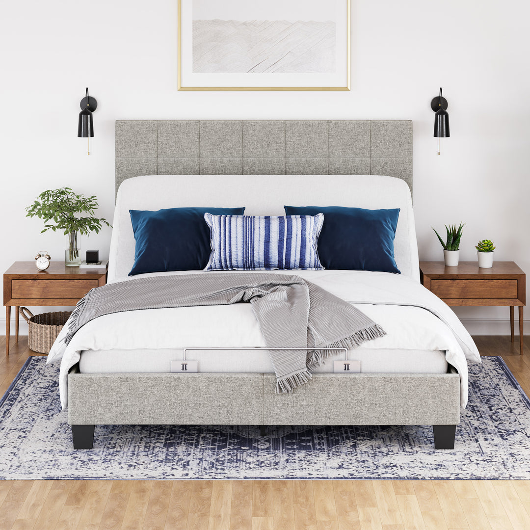 An adjustable power base bed frame with head up, with a white comforter, and pillows in a bedroom setting.