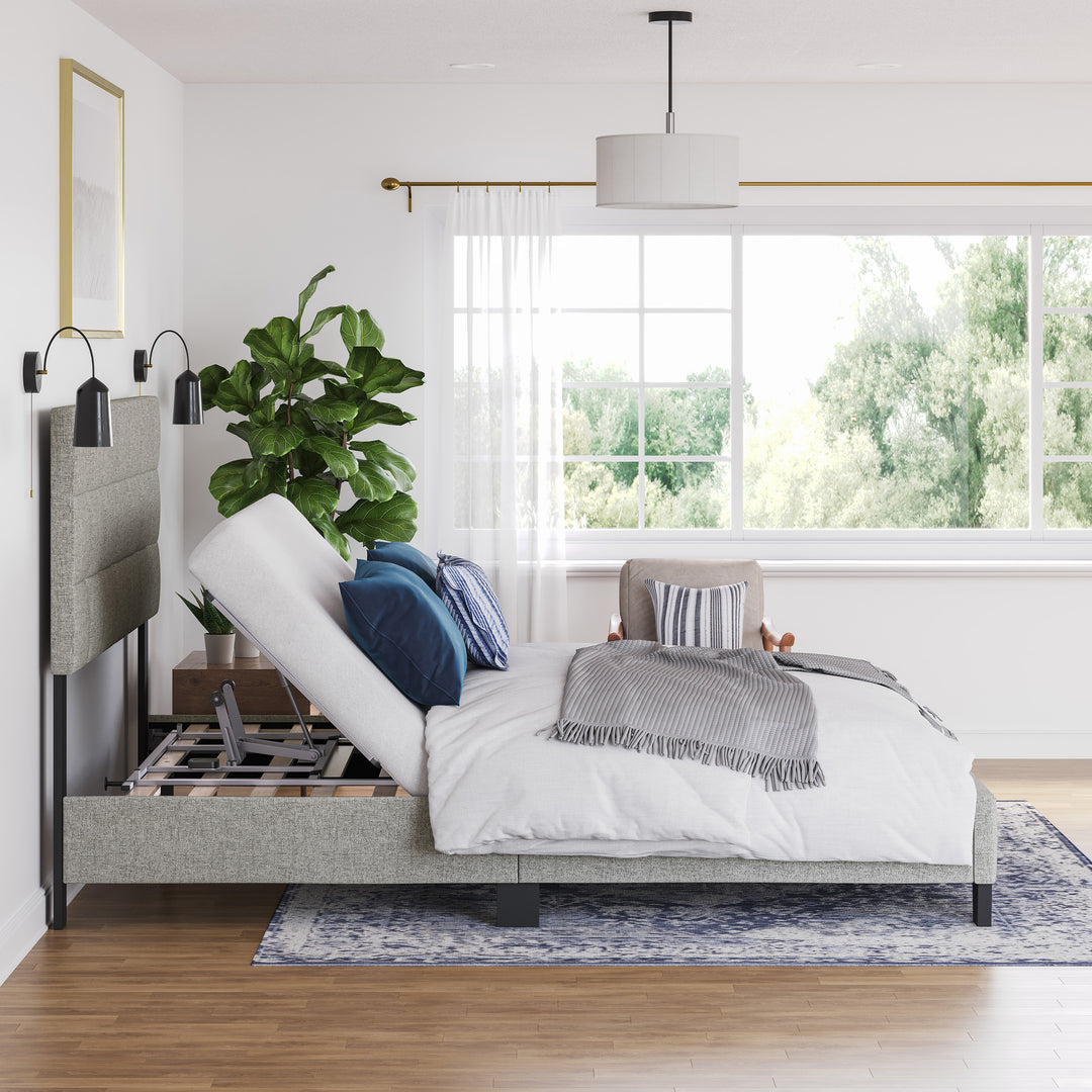 An adjustable power base bed frame with head up, with a white comforter, pillows, and a plant decoration in the bedroom setting.