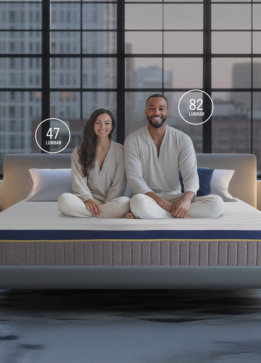 Man and woman sitting on a mattress with a cityscape in the background