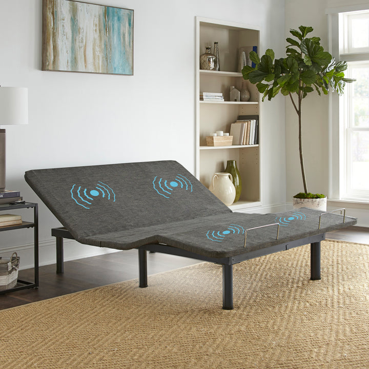 An adjustable power base bed with a gray fabric surface and blue illuminated control buttons, placed in a well-lit living room setting.