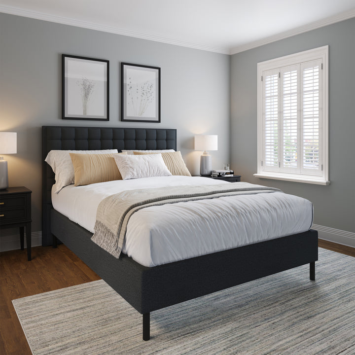 a mattress on platform bed frame with a custom fitted black fabric cover, placed in a room with a windowsill decor and a lamp on the nightstand.