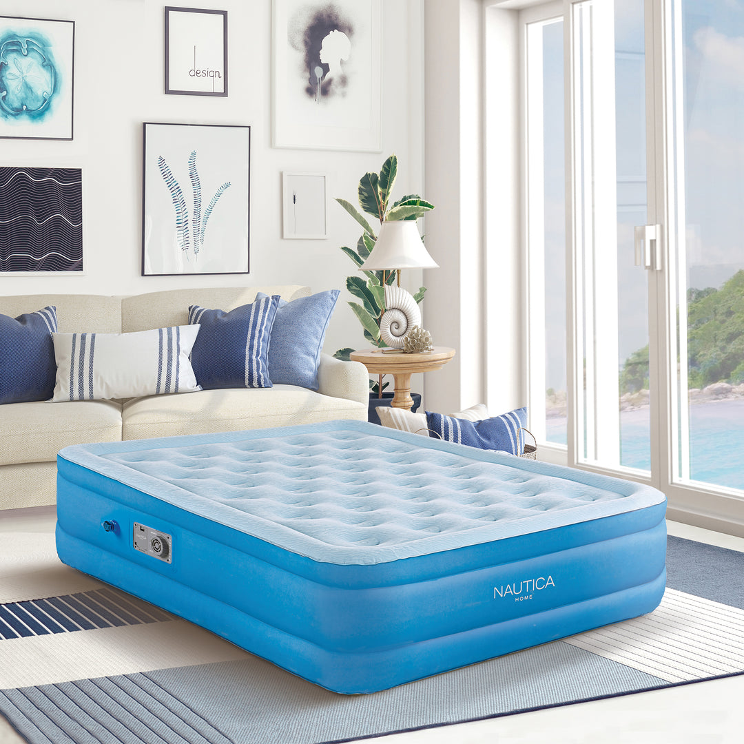 Blue inflatable mattress in a room with a couch and large window.
